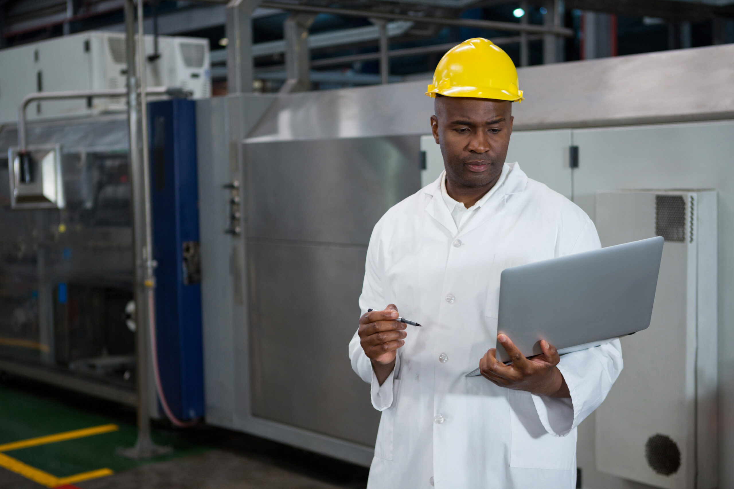 Serious male worker using laptop in manufacturing industry
